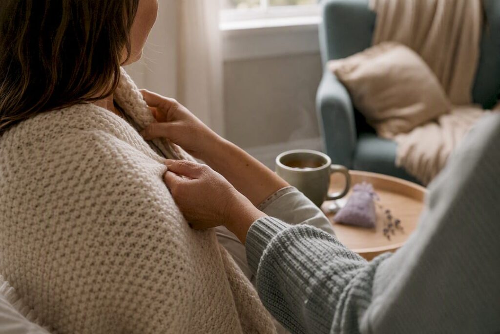 Hands wrapping a warm blanket around new mother